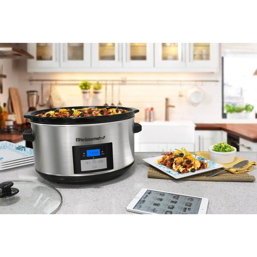 The stainless slow  cooker is displayed on kitchen counter next to serving dishes and food.