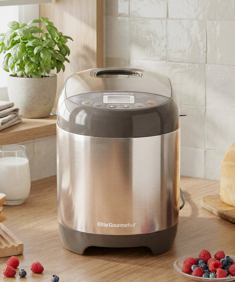 Stainless steel bread maker on a kitchen counter with berries and milk in the background