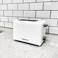 The 2 slice white toaster placing on a marble countertop. 