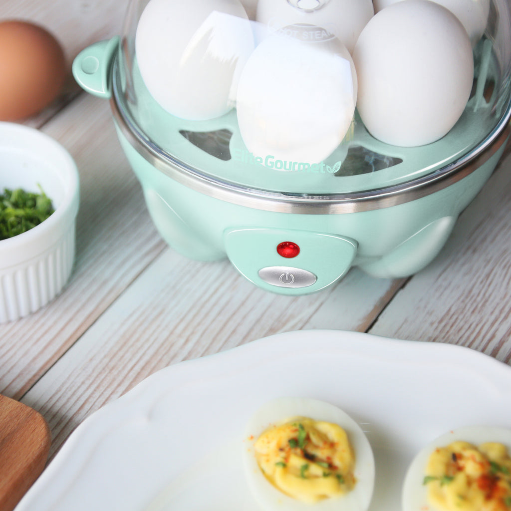 Egg cooker power indicator light is lit red. Plate of deviled eggs next to egg cooker.