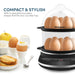 COMPACT & STYLISH With a beautiful rounded shape that fits any counter top. Elite Gourmet 14-Egg Programmable Easy Egg Cooker on white background with breakfast foods.