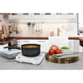 Flat Burner on kitchen counter with saucepan cooking soup.  Next to various serving plates, cutting board and ingredients.