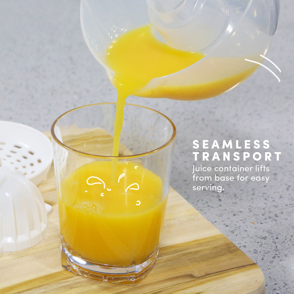 SEAMLESS TRANSPORT Juice container lifts from base for easy serving. Orange juice transferring into the glass. 