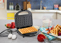 Waffle Maker set on kitchen counter next to ingredients and cooked waffles.