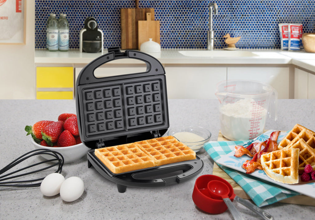 Waffle Maker set on kitchen counter next to ingredients and cooked waffles.